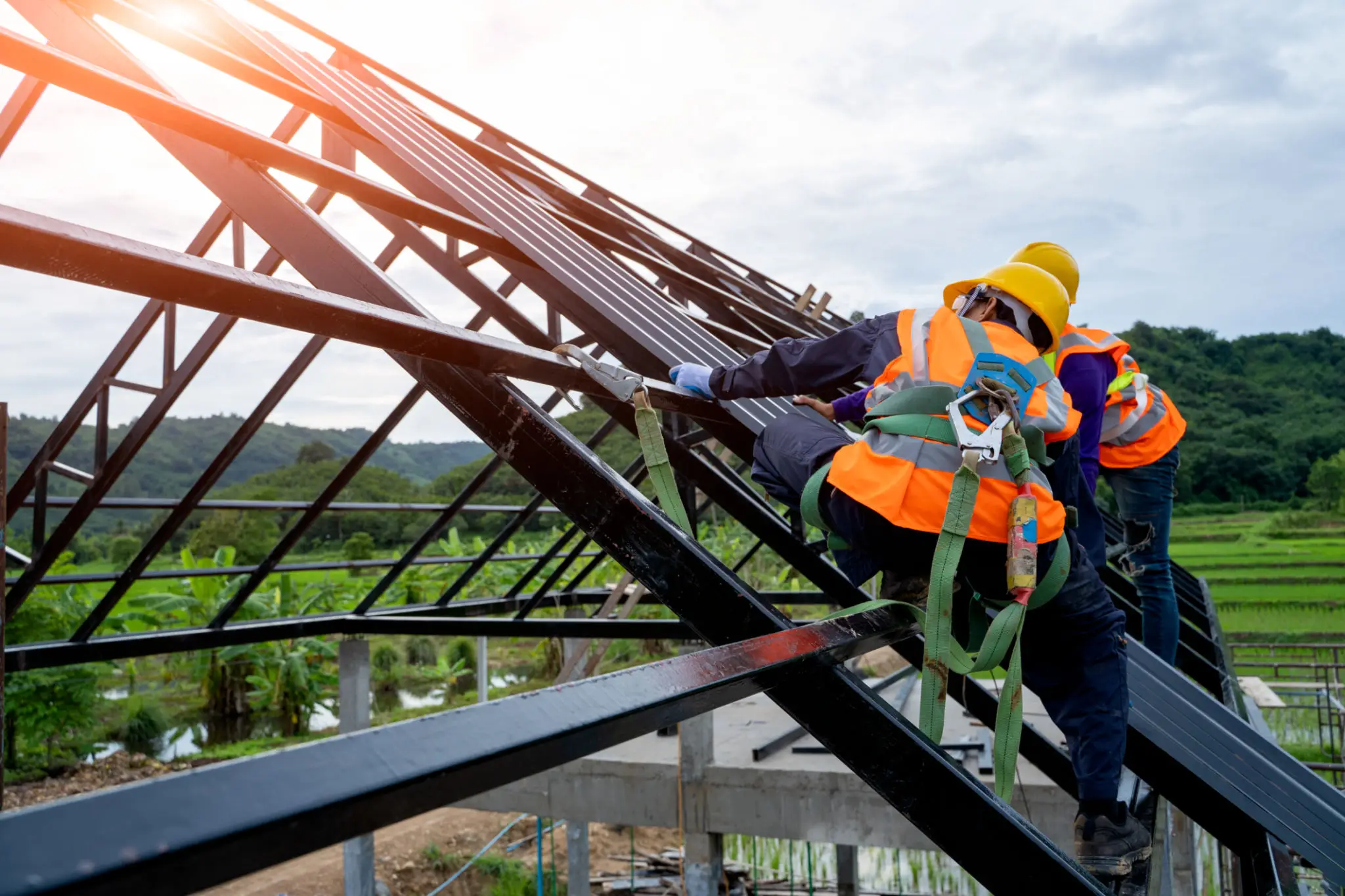Construction workers on a metal roof structure.